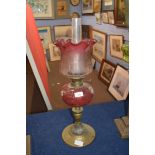 Late Victorian oil lamp with frilled cranberry tinted shade with floral decoration, clear glass