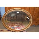 20th century oval bevelled wall mirror set in a gilt finish frame