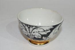 Small bowl decorated in black and white with a design by Fornisetti, with a gilt line below, the