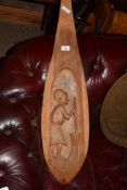 ETHNIC HARDWOOD PADDLE SHAPED WALL CARVING DECORATED WITH A FIGURE GRINDING MAIZE
