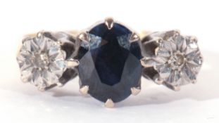 Sapphire and diamond set three stone ring centring an oval shaped sapphire flanked by two small