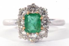 Emerald and diamond cluster ring featuring a rectangular step cut emerald, claw set and raised