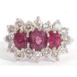 Ruby and diamond cluster ring, a design featuring three graduated oval shaped rubies, surrounded