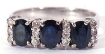 Three stone sapphire and diamond ring, the three oval shaped dark sapphires highlighted between with