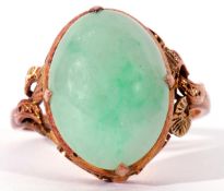 Modern jade ring of oval cabochon shape, cardinal set in a scroll pierced mount, stamped 22K, size