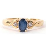 Modern sapphire and diamond ring centring an oval faceted sapphire raised between two small diamonds
