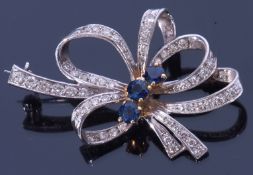 18ct white gold, sapphire and diamond brooch, a tied ribbon design centring three round cut small