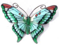 Silver and enamel butterfly brooch, the outstretched wings and body decorated in green, red and blue