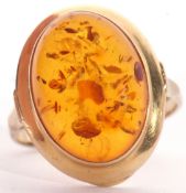 Modern yellow metal and amber dress ring, the oval cabochon amber centre 16 x 12mm, bezel set in a