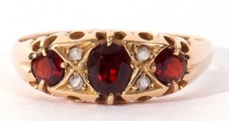 18ct gold garnet and diamond ring, centring an oval faceted garnet between two round old cut garnets