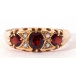 18ct gold garnet and diamond ring, centring an oval faceted garnet between two round old cut garnets