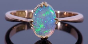 18ct stamped opal ring featuring an oval cabochon opal, cardinal set and raised between tapering