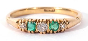 Antique diamond and emerald ring featuring three graduated old cut diamonds and two cushion cut