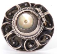 White metal filigree poison ring, the hinged mother of pearl lid opening to a vacant reservoir,