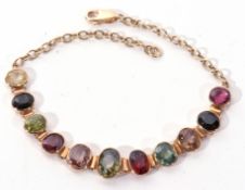 A 750 stamped multi-gem set line bracelet, graduated with various precious stones including peridot,