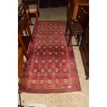 20TH CENTURY WOOL FLOOR RUG DECORATED WITH MEDALLIONS ON A RED BACKGROUND, 125CM LONG