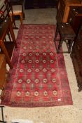 20TH CENTURY WOOL FLOOR RUG DECORATED WITH MEDALLIONS ON A RED BACKGROUND, 125CM LONG