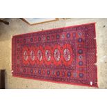 20TH CENTURY MIDDLE EASTERN WOOL FLOOR RUG DECORATED WITH GEOMETRIC DETAIL AND LOZENGES ON A RED