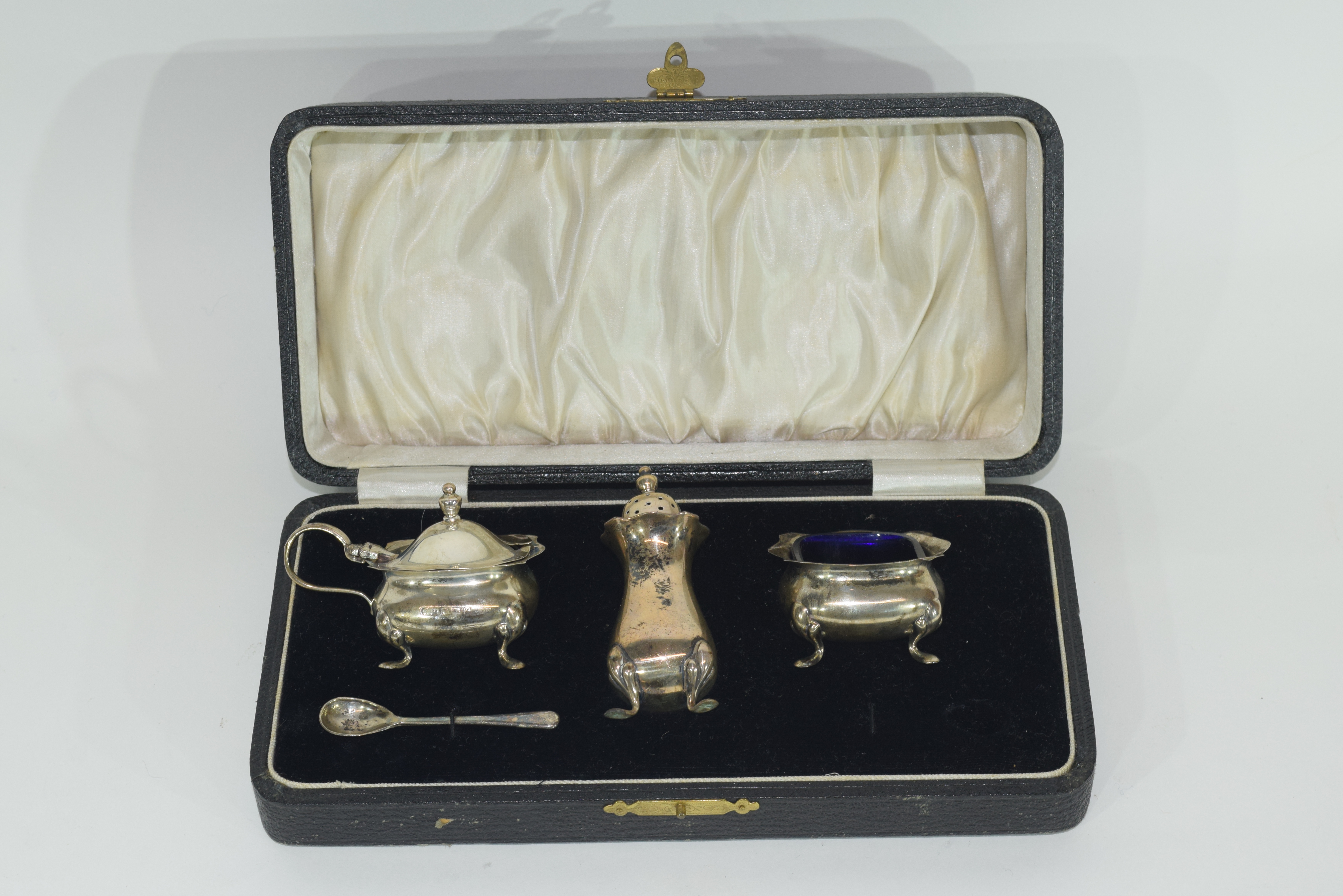 Cased three piece silver condiment set comprising a hinged lidded mustard and liner, open salt and
