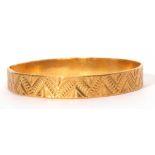 A high-grade yellow metal solid cast bangle, chased & engraved with a continuous geometric design