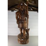 20TH CENTURY CARVED HARDWOOD FIGURE WITH DOG RAISED ON A PLINTH BASE, 90CM HIGH