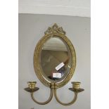 SMALL OVAL BRASS FRAMED BEVELLED WALL MIRROR WITH ATTACHED PAIR OF CANDLESTICKS