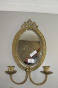 SMALL OVAL BRASS FRAMED BEVELLED WALL MIRROR WITH ATTACHED PAIR OF CANDLESTICKS