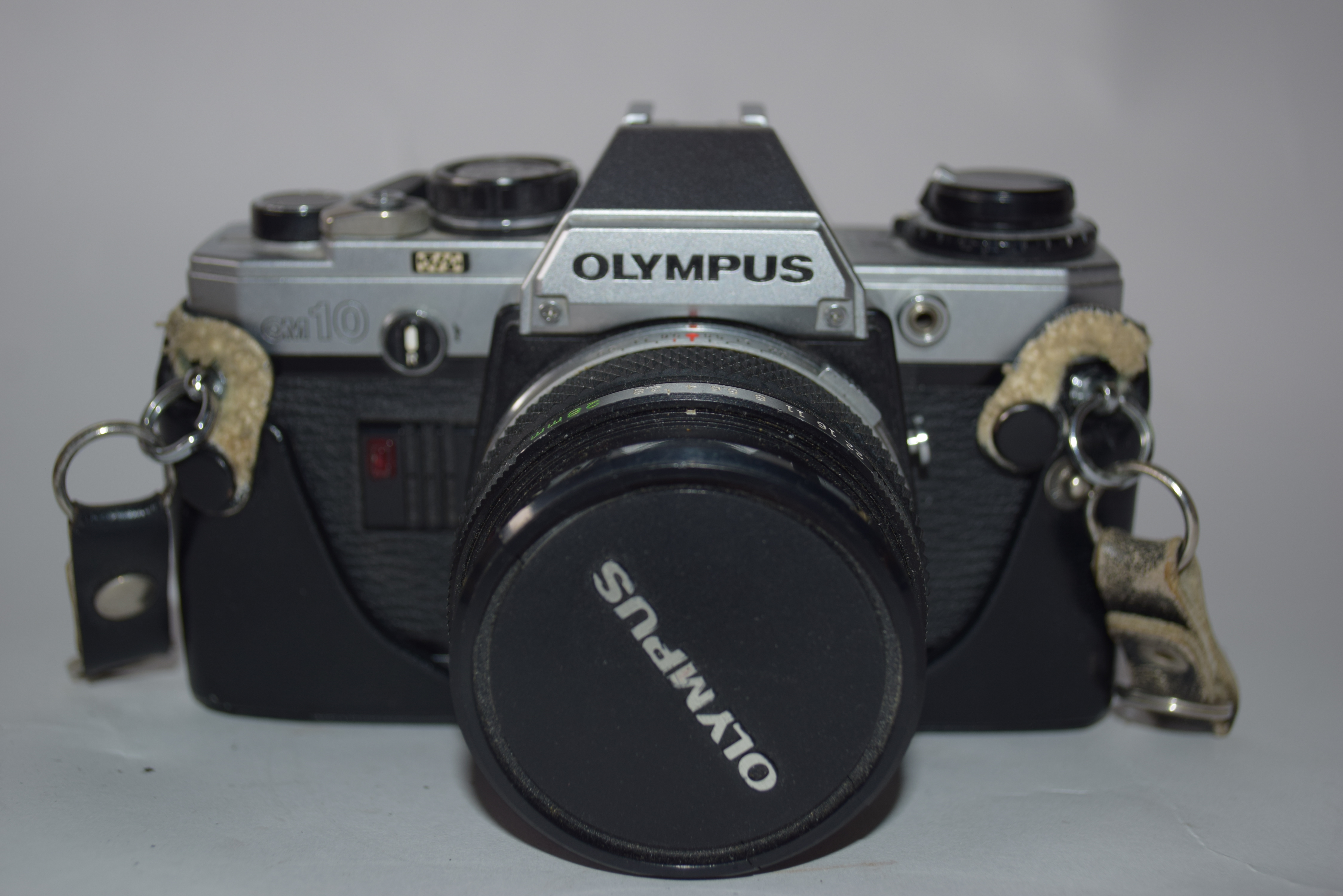 Olympus OM-10 film camera with accessories including strap, flash and Makinon MC35-100mm lens and