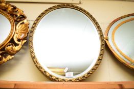 20TH CENTURY OVAL BEVELLED WALL MIRROR IN GILT FINISH FOLIATE MOULDED FRAME, 54CM WIDE