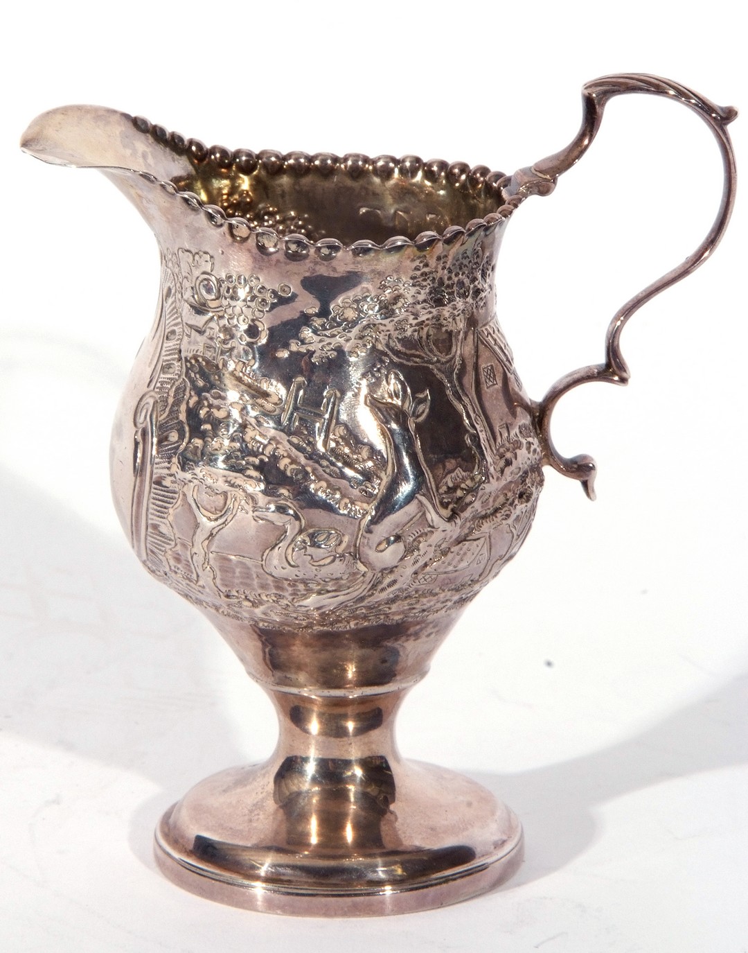 George III silver cream jug of slender helmet shape, sweeping handle and beaded rim, on a raised