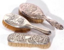 Group of three silver backed dressing table hand brushes comprising two brushes with cherub