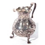 George II silver cream jug of baluster form with looped and scrolled handle and raised on three