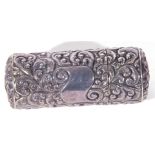 White metal or plated small cylindrical container with hinged lid decorated with scrolled foliage,