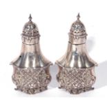 Pair of Edward VII silver pepperettes of shaped baluster form, the bodies decorated with scrolled