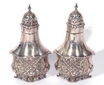 Pair of Edward VII silver pepperettes of shaped baluster form, the bodies decorated with scrolled