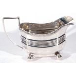 Edward VII silver cream jug, the body with looped handle and ribbed decoration raised on four ball