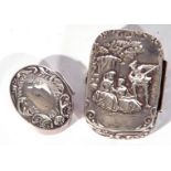 Two white metal pill boxes, one of hinged rectangular form, the lid decorated with figures in a