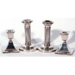 Pair of George V small silver candlesticks, the stems of ribbed decoration raised on spreading