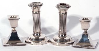 Pair of George V small silver candlesticks, the stems of ribbed decoration raised on spreading