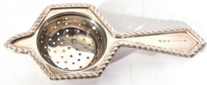 George V silver tea strainer of hexagonal angular form with a lug support, applied with gadrooned