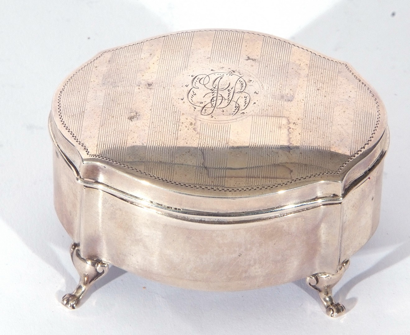 George V silver ring box of shaped oval form, the slight domed lid with central monogram between