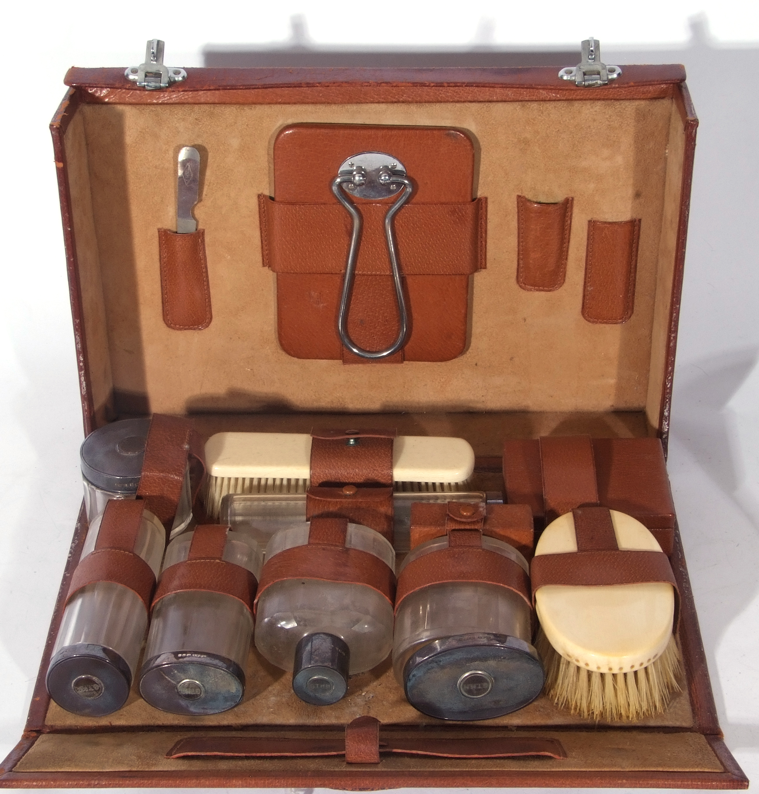 George V brown leather vanity case containing a selection of silver topped clear glass jars and