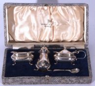 George VI cased silver condiment set comprising a lidded four-footed pepper, a mustard with hinged