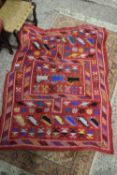 RED FLOOR RUG WITH STYLISED DECORATION OF ANIMALS AND FLOWERS ON A RED BACKGROUND