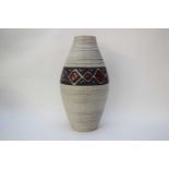 Large vase with ribbed design and central panel with red and white design on a dark grey background,