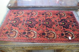 Small Middle Eastern wool rug or prayer mat decorated with black and orange stylised foliage on a