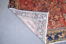 Hamadan wool carpet decorated with large central panel of stylised foliage on a red background,