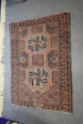 Middle Eastern prayer rug decorated with large lozenges on a principally orange/rust background, rug