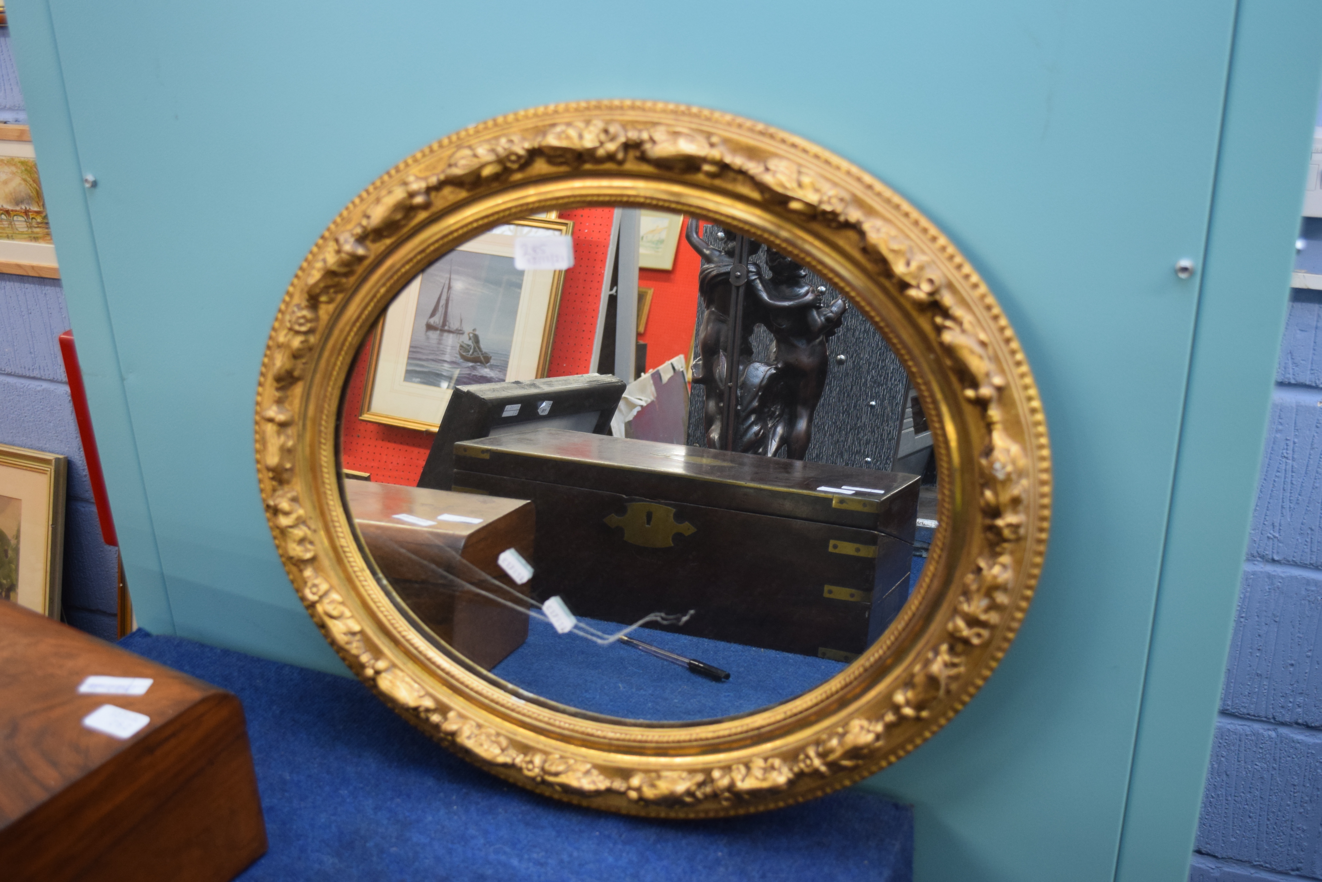 20th century gilt framed oval wall mirror, frame moulded and with foliate detail, 59cm wide