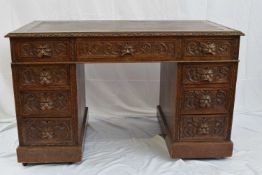 Victorian Gothic carved oak twin pedestal desk with nine drawers and an inset rexine writing